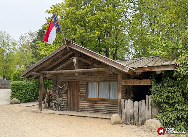 Leerstehender, rustikaler Kiosk Tipi-Lager im Abenteuerland des Hansa-Park mit Holzfassade, Flagge und Wagenrad