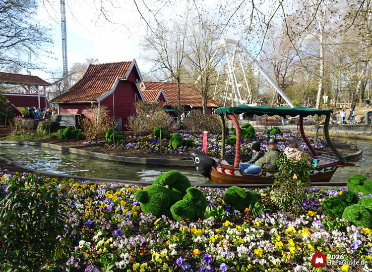 Blumenmeerbootsfahrt im Hansa-Park mit Boot, Blumenbeeten und Schiffschaukel im Hintergrund