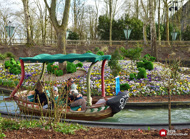 Familienfreundliche Blumenmeerbootsfahrt im Hansa‑Park durch blühende Gartenlandschaft mit Figuren, Wasserkanal und liebevoll platzierten Rasen-Hasen