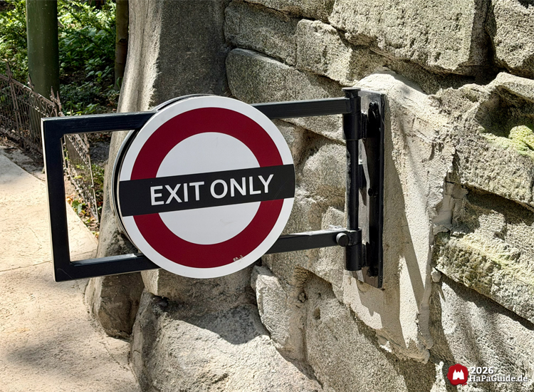 Steintor mit rundem Schild und der Aufschrift 'Exit Only' am Ausgang des Cornwall Coaster im Hansa-Park, umgeben von Steinmauern und Pflanzen