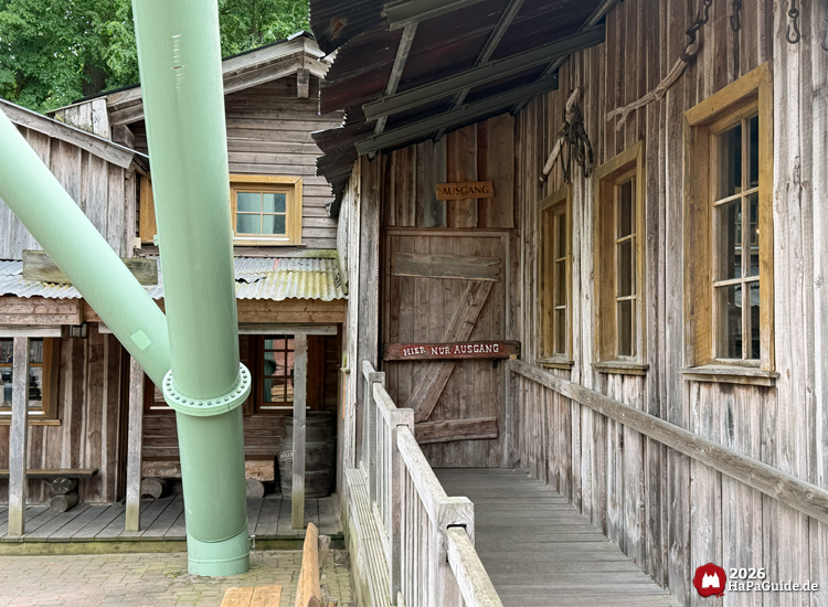 Stationsgebäude mit Schild 'Ausgang' und 'Hier nur Ausgang' der Crazy Mine im Hansa-Park, daneben grüne Stahlstützen vom Schwur des Kärnan