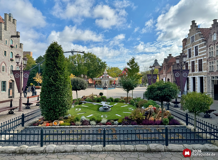 Blumenuhr im Hansa-Park mit Ziffern und herbstlicher Bepflanzung, umgeben von historischen Hansefassaden und blauem Himmel