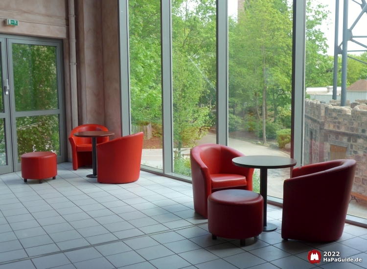 Sitzbereich mit roten Ledersesseln entlang einer großen Glasscheibe