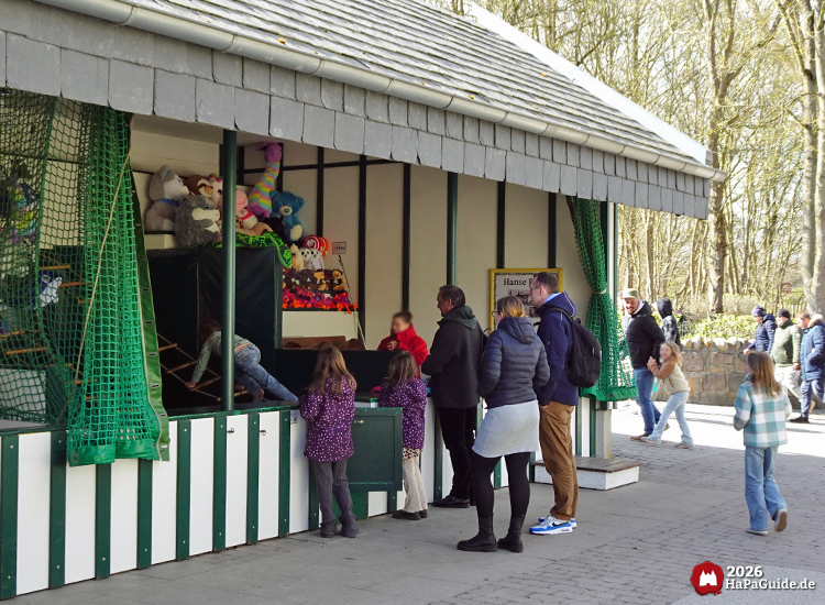 Familien und Kinder spielen an einem Wurfstand im Hansa-Park, umgeben von Plüschgewinnen