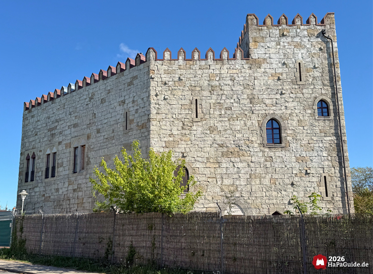 Rückseite der massiven Steinburg Palacio de Braga im Hansa-Park mit Zinnen, schmalen Fenstern und klar blauem Himmel