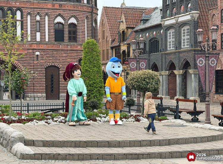 Hansa-Park Figuren Awilda und Flipsi in der Themenwelt Hanse in Europa vor dem Holstentor mit Kind
