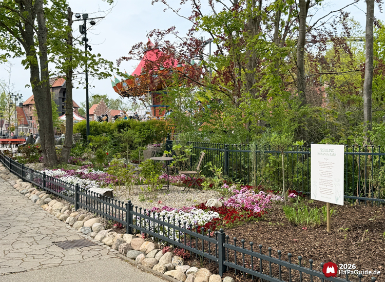 Bepflanztes Staudenbeet mit bienenfreundlichen Blumen entlang eines Weges im Hansa-Garten des Hansa-Parks, im Hintergrund dreht der Hanse-Flieger