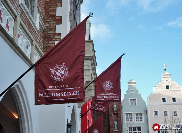 Fahnen des Restaurants Weltumsegler an historischer Altstadtfassade bei sonnigem Wetter