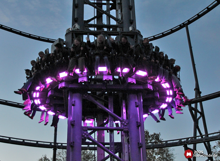 Highlander - Fahrgäste hängen in der purpur beleuchteten Gondel über der Basis