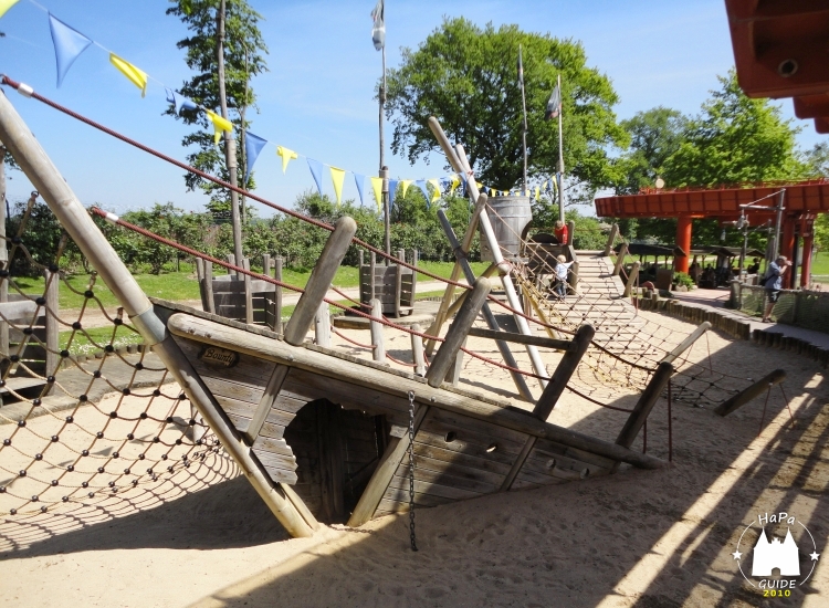 Ein Holzspielschiff halb im Sand versunken
