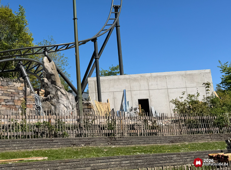 Baustelle des Cornwall Coaster im Hansa-Park mit Betongebäude des zukünftigen Roche Rocks, Felsgestaltung und geschwungenen Schienen unter blauem Himmel