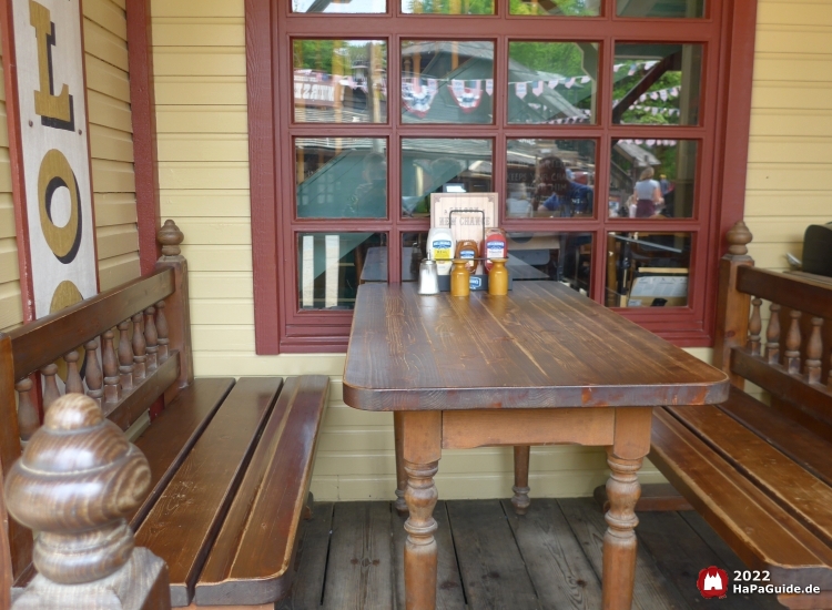 Ein Tisch mit zwei langen Bänken auf der Veranda des Saloons New Chance