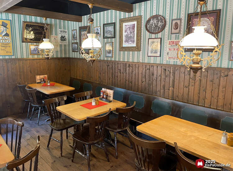 Saloon New Chance - Holztische entlang einer grün gestreift tapezierten Wand