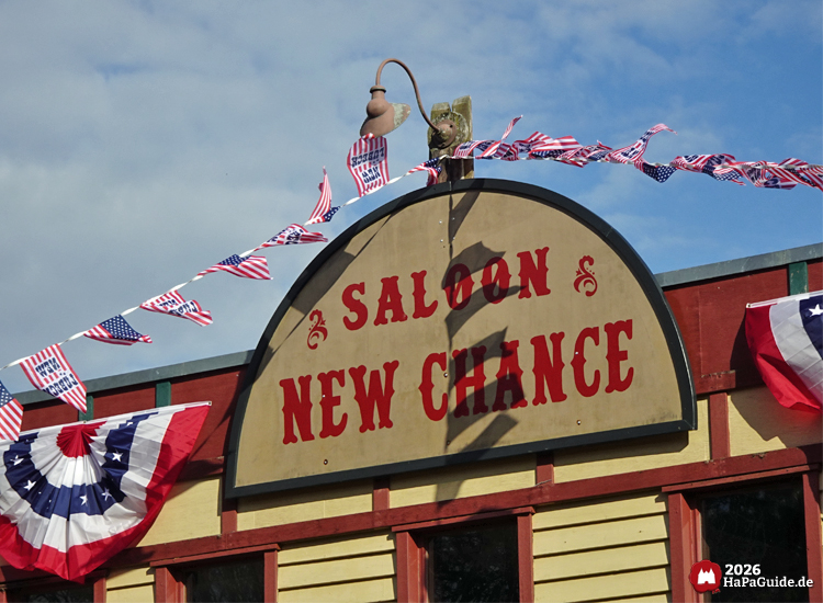 Western Fassade des Saloons New Chance mit bunter USA Beflaggung und typischer Westernarchitektur
