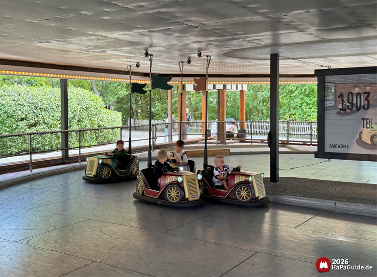 Kinder fahren kleine Oldtimer-Autos auf der 1903 Somerset Traffic Bahn im Hansa-Park, überdachtes Fahrgeschäft mit grüner Umgebung und sommerlicher Atmosphäre