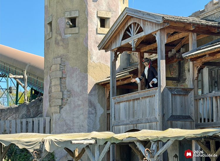 Piratenfigur auf dem Balkon der Attraktion Störtebeker’s Kaperfahrt im Hansa-Park, trägt dunkle Kleidung und Dreispitz, steht vor einem Turm aus Stein und Holz unter blauem Himmel