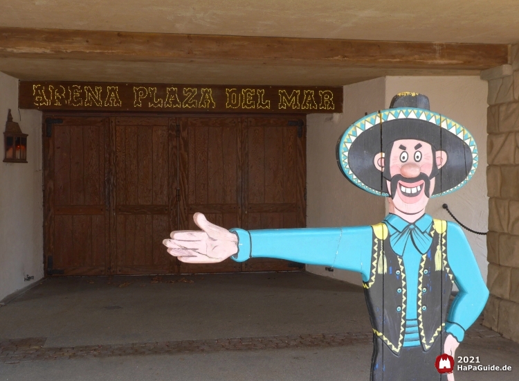 Eine Holzfigur mit Sombrero vor dem leuchtenden Schriftzug der Arena Plaza del Mar